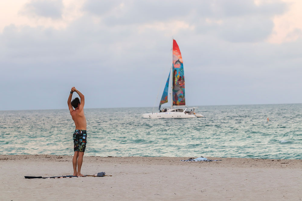 Young men doing yoga on the beach in Miami South Beach